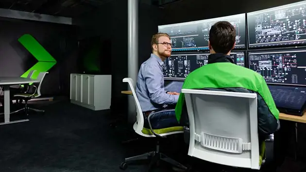 An operator and automation engineer discuss process improvements in a remote control room