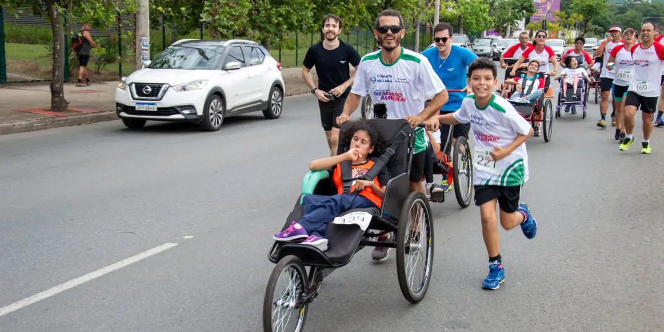 Man and a boy running and pushing another child in a wheelchair